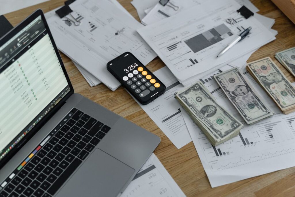 Small business payroll worksheet with a calculator, financial reports, and cash on a desk