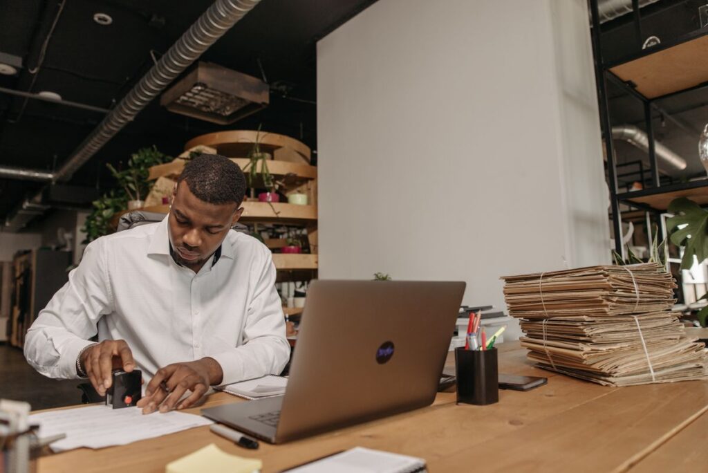 Office worker stamping documents beside stacked record folders