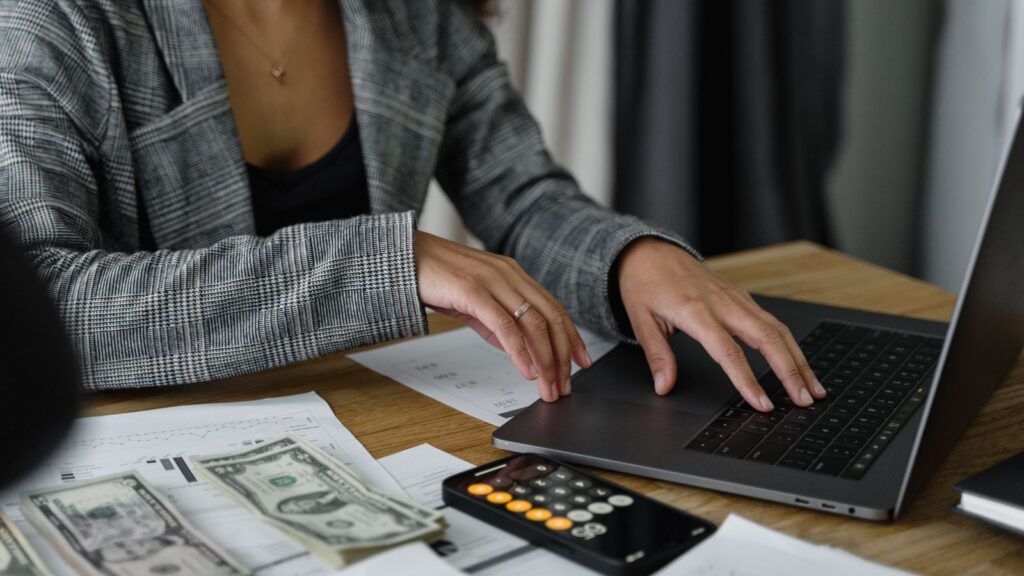 Small business owner reviewing financial records and using a calculator at a desk