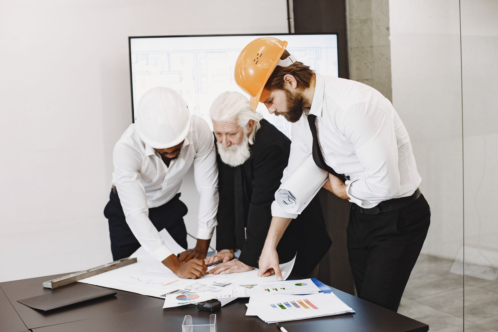 Three professionals reviewing charts and plans on a conference table, the kind of review that answers how to pay yourself as a business owner