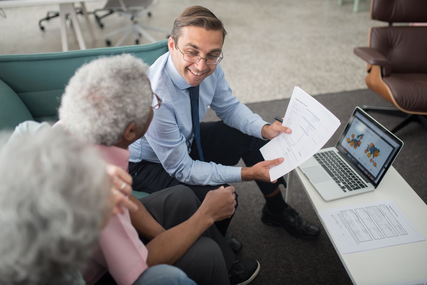 Adviser going over household financial paperwork with an older couple in an office