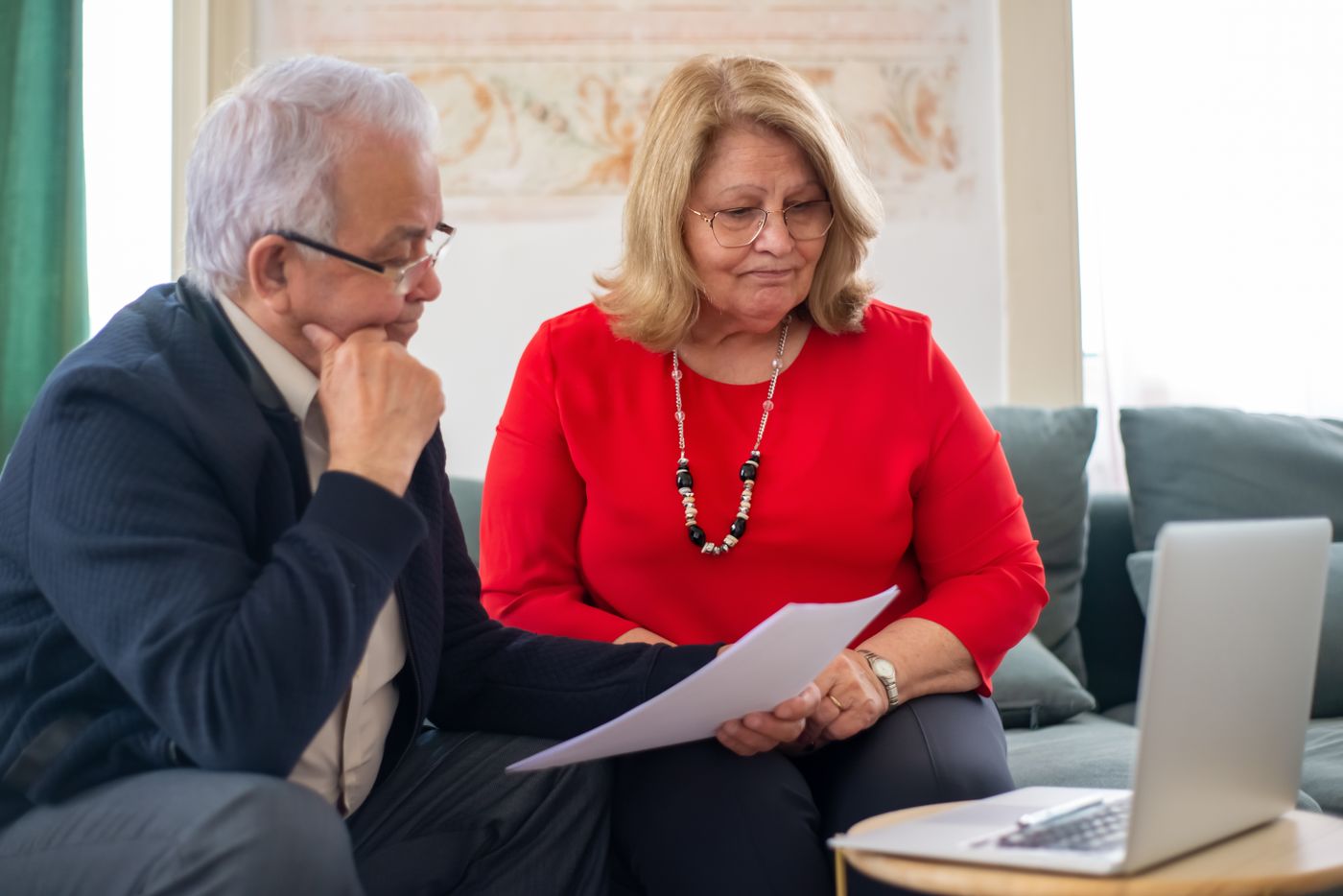 Older couple reviewing financial documents together at a kitchen table at home