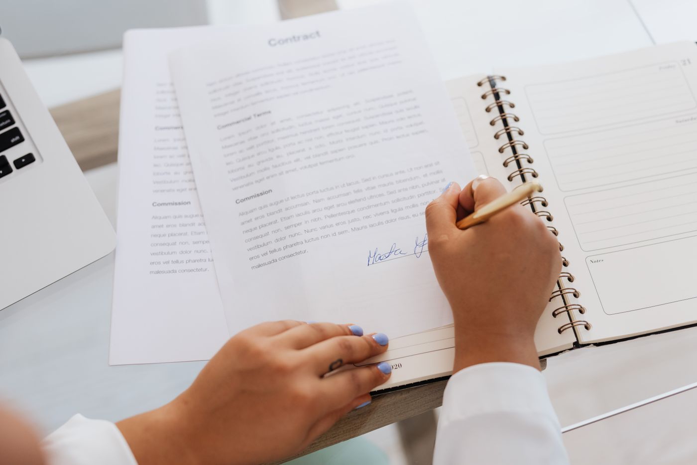 Hands signing a contract on a desk beside official documents delivered to a registered agent