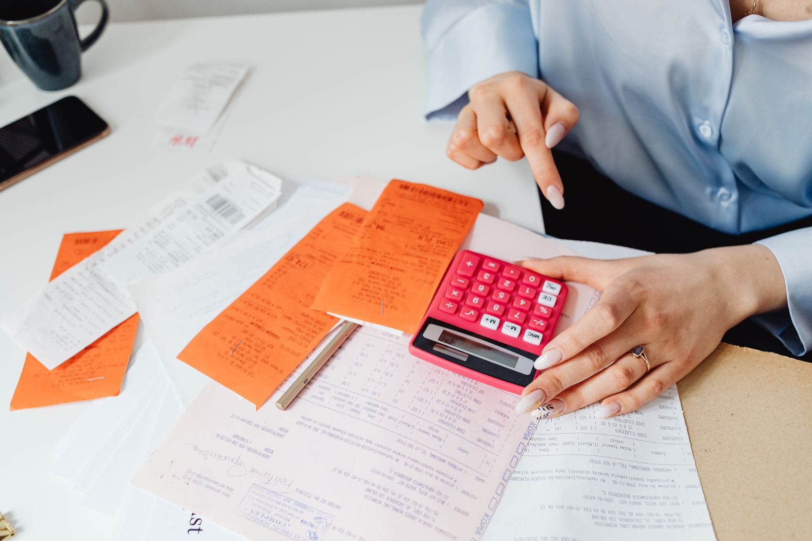 Sorting a stack of receipts with a calculator during a bookkeeping cleanup