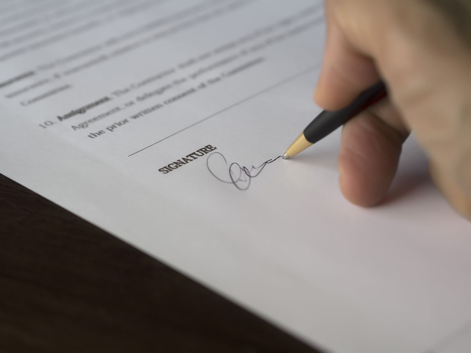 Hand signing worker classification paperwork on a wooden desk